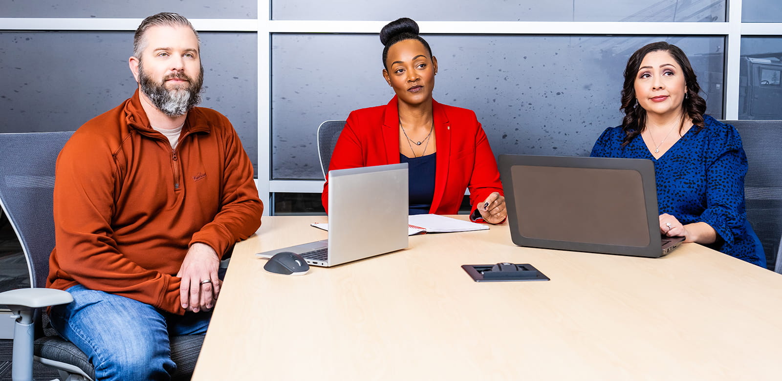 Three employees sit together in a meeting room