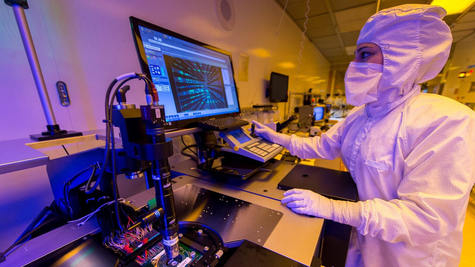 An engineer examines a semiconductor on a computer.