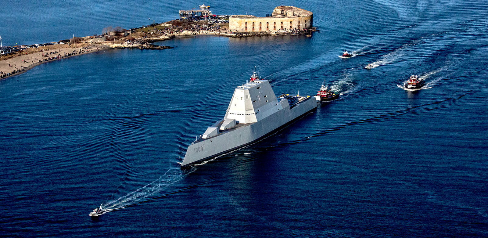 Zumwalt destoyer being guided by tugboats