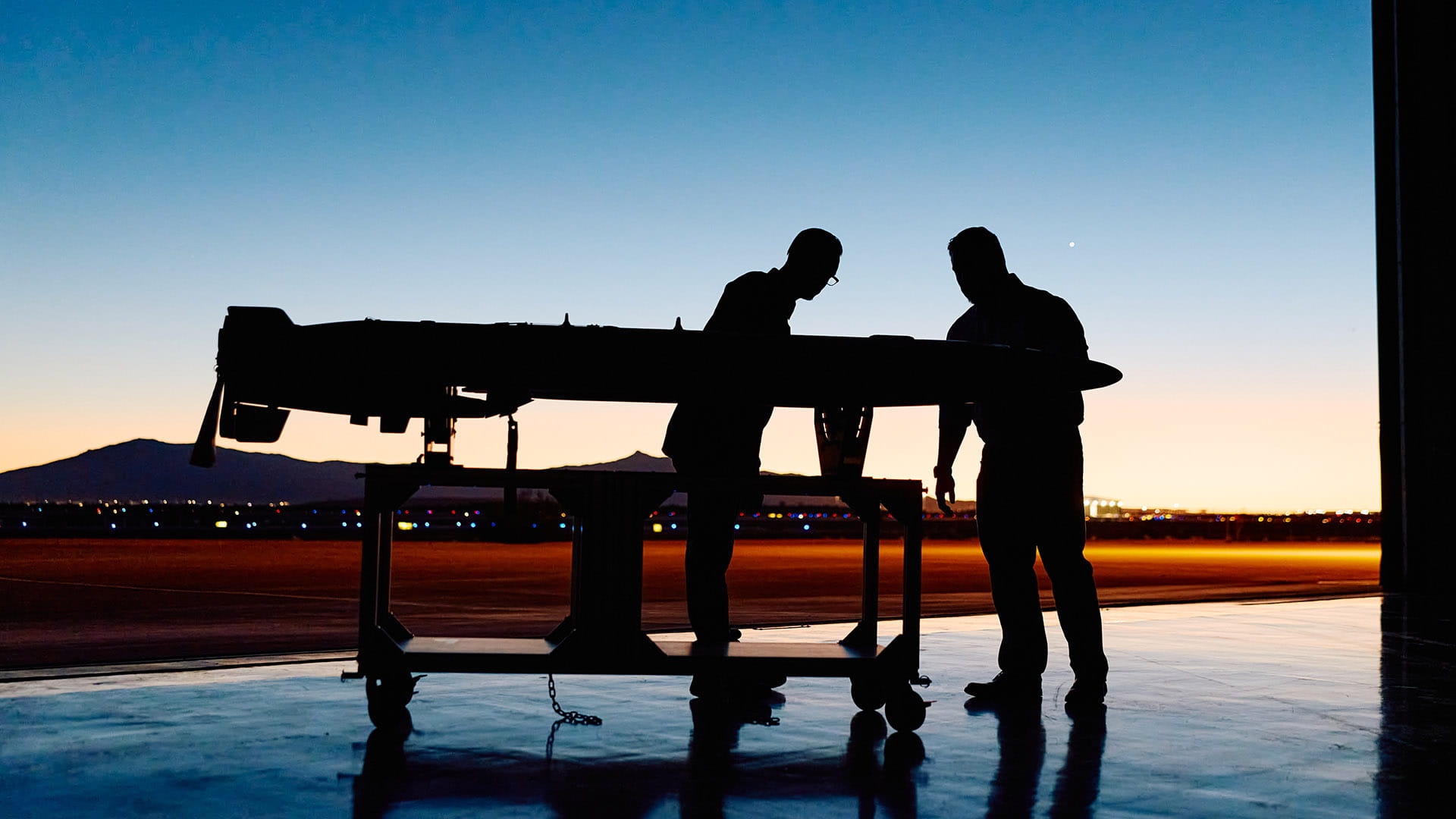 two technicians inspect a MALD decoy on a stand